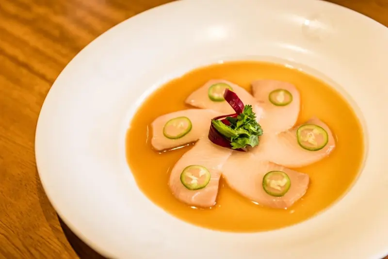 Plato de pescado crudo con jalapeño en un caldo cítrico