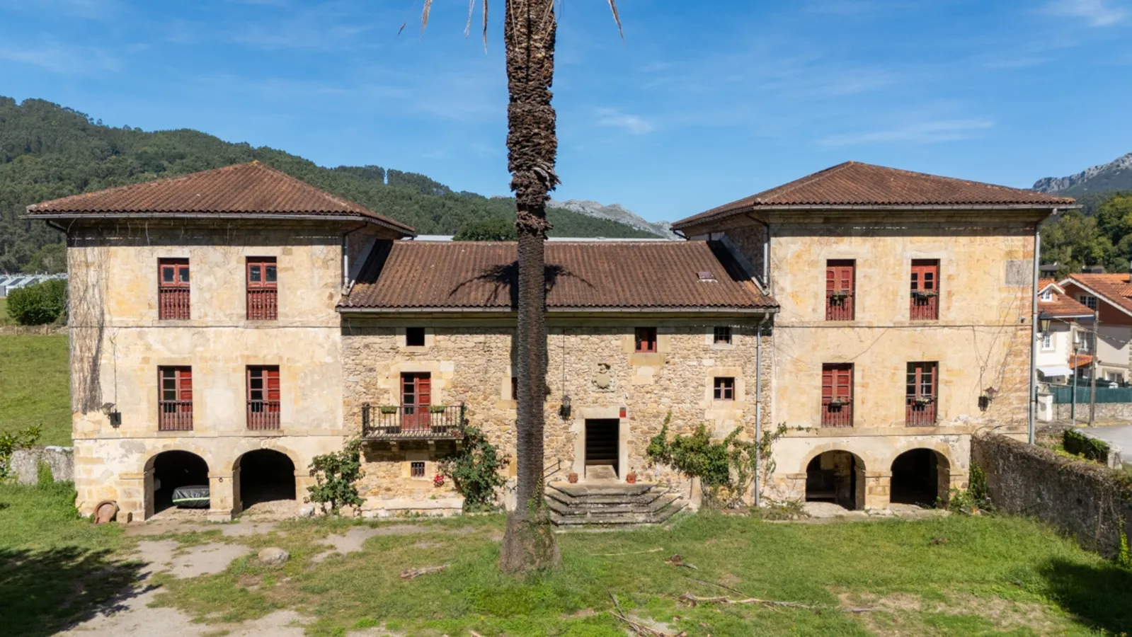 Fachada de piedra de Casa Pinta, palacio del siglo XIX en Guriezo, con una palmera en el jardín